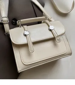 Détail du sac à main crème rectangulaire avec texture plissée et finitions argentées