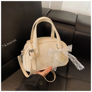 Détail du sac Boston en cuir verni crème avec nœud en dentelle et perles