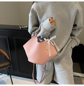 Borsa a secchiello rosa in pelle con fiocco in pizzo bianco e pendente di perle