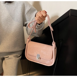 Close-up of a pink suede crossbody bag featuring a classic silver metal push-lock closure