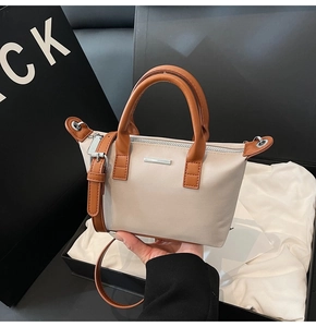 Close-up of a two-tone bucket bag with silver zipper detail and detachable shoulder strap