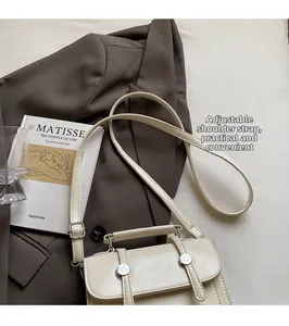 Petit sac à main beige chic posé sur un blazer avec bandoulière réglable