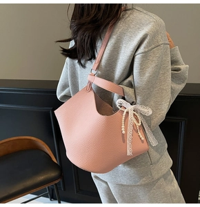 Detailed view of pink lychee texture shoulder bag with lace bow and pearl charms