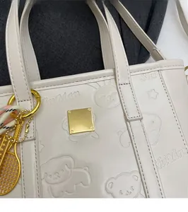 Detail of white PU leather bucket bag with cute cartoon embossing and gold tennis racket charm