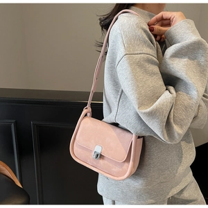 Side view of a pink minimalist crossbody bag with suede texture and silver metal twist lock