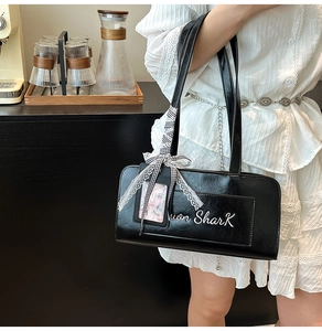 Dettaglio borsa sottobraccio in similpelle nera con logo won SharK e fiocco a scacchi