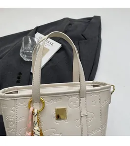 Close-up of white embossed bucket bag with cartoon animal patterns and golden hardware detail