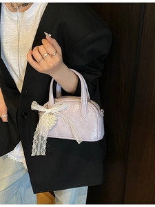 Sac polochon mini lilas chic avec nœud en dentelle et pendentif cœur perlé tenu par un modèle