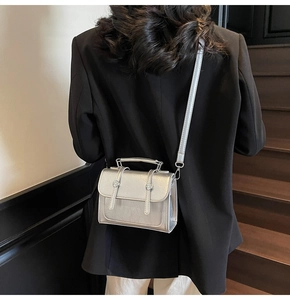 Sac à main en PU argenté avec rabat et bandoulière sur une veste de tailleur noire