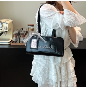 Dettaglio della borsa a spalla vintage in pelle verniciata nera con fiocco in pizzo