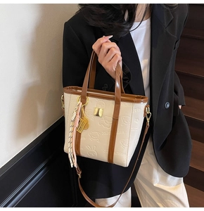 Detail view of cream bucket bag with cute floral embossing and golden abacus charm