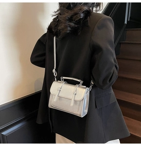 Sac carré argenté brillant avec boucle métallique et plis accordéon en gros plan