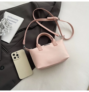 Detail of light pink bucket bag with lychee grain leather texture and metal trim
