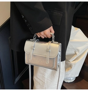 Gros plan d'un sac à main argenté métallisé avec doubles boucles vintage et poignée