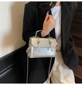 Détail d'un sac à bandoulière argenté métallisé avec doubles sangles et poignée en métal