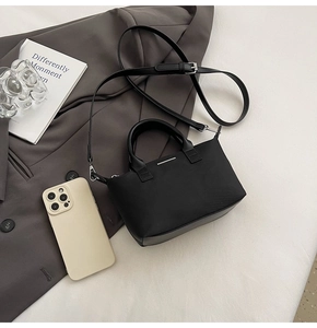 Detail of black mini bucket bag with silver metal bar accents and adjustable strap