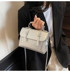 Détail d'un sac argenté à texture grainée et fini métallisé sur un costume noir