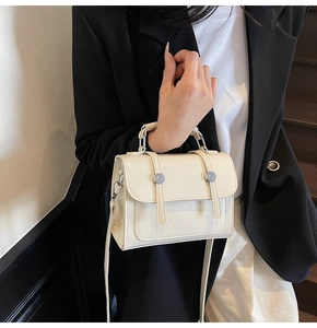 Détail d'un sac à main minimaliste crème avec lanières décoratives et boucles argentées