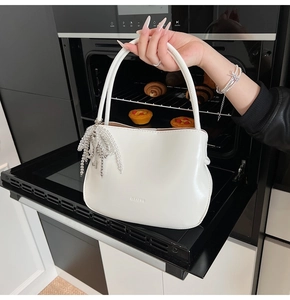 Nahaufnahme einer weißen Leder-Eimertasche mit silbernen Perlen und Schlüsselanhänger