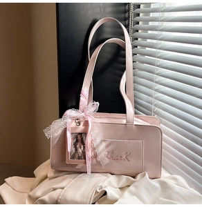 Dettaglio borsa in similpelle rosa con fiocco in pizzo, ricamo Shark e portafoto