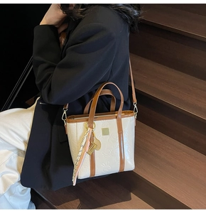 Detail of embossed rabbit pattern on cream leather bucket bag with brown handles