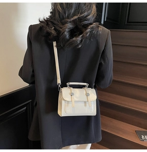 Détail du mini sac bandoulière blanc crème avec finitions argentées porté par le modèle