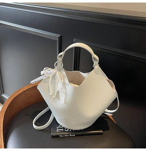 Dettaglio della borsa a secchiello in pelle verde menta con charm in perle e pizzo