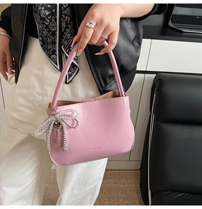 Detail der rosa Leder-Beuteltasche mit silberner Perlen-Schleife und Herzanhänger