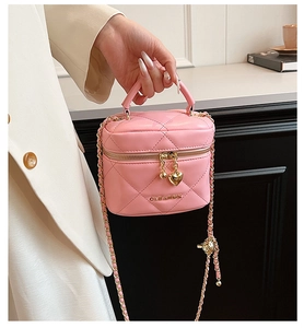 Gros plan d'un sac boîte matelassé rose avec pendentif cœur et bandoulière chaîne