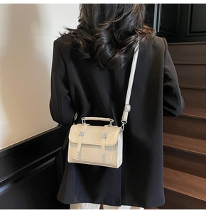 Modèle portant un sac bandoulière en cuir PU crème avec boucle argentée et poignée