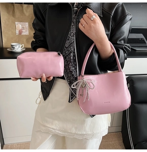 Detailaufnahme eines rosa Eimer-Taschensets mit Schleifenanhänger am Modell getragen
