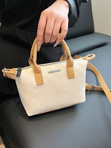 Minimalist cream canvas bucket bag with tan leather straps and silver logo detail