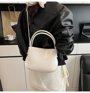 Detail der weißen Leder-Beuteltasche mit CLEARE-Logo und schmalem Schultergurt