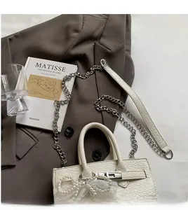 Detail of lychee pattern leather bag with pearl lace bow and metal chain strap