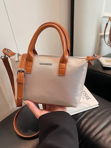 Minimalist beige bucket bag with brown leather handles and adjustable shoulder strap