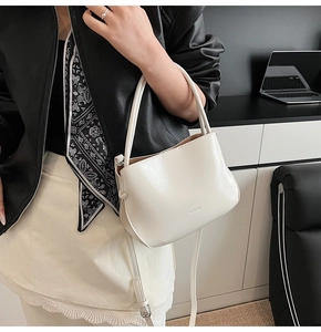 Detail der minimalistischen weißen Beuteltasche mit Lederfinish und dünnem Schultergurt