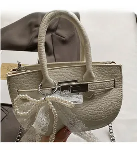 Detail of lychee textured cream handbag with silver hardware and lace pearl bow charm