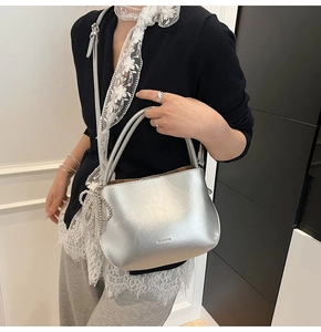 Nahaufnahme der silbernen Beuteltasche mit Logo-Prägung und Herz-Kettenanhänger