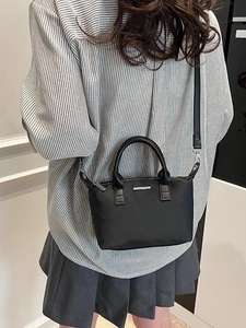 Minimalist black matte bucket bag with silver logo plate for casual daily commuting