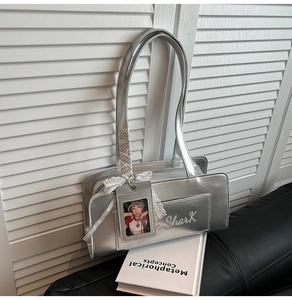 Dettaglio della borsa metallica argento con ricamo Shark e fiocco di pizzo su base nera