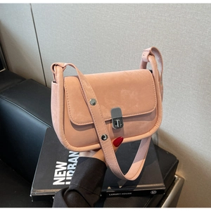 Detail of light pink suede shoulder bag featuring a silver twist lock and rivet accents
