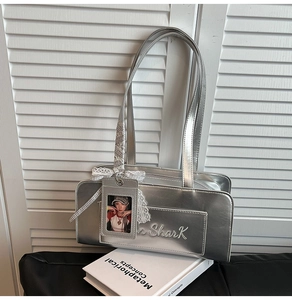 Dettaglio della borsa a spalla argento metallizzato con fiocco in pizzo e ciondolo chic