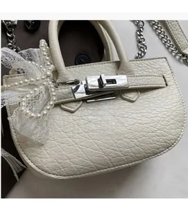 Close-up of creamy white bucket bag featuring lychee texture and pearl bow detail
