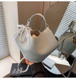 Dettaglio borsa in pelle azzurra con fiocco di pizzo e perle e sacchetto interno beige