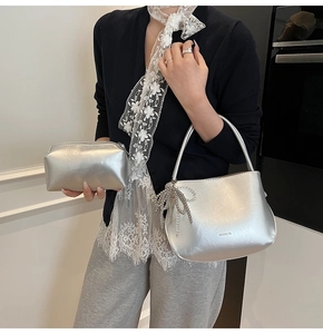 Details einer silbernen Metallic-Handtasche mit Schleifenkette und Kosmetiktasche