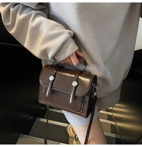 Détail d'un sac à main vintage en cuir marron avec boutons argentés et bandoulière