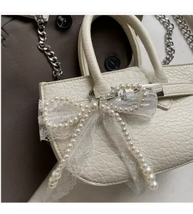 Close-up of white lychee texture leather bag with a large lace bow and faux pearl accents