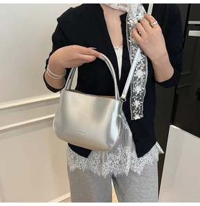 Detail der silbernen Satteltasche mit Metallic-Finish und Logo-Prägung in der Hand