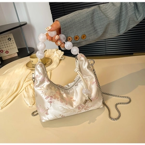 Detail of plum blossom embroidery on silk handbag with beaded handle and silver chain