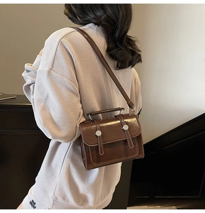 Vue arrière du mannequin portant un sac à bandoulière vintage en cuir marron poli et boucle